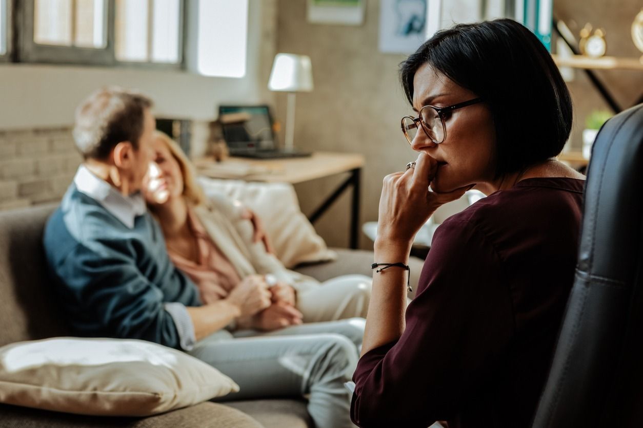 Una mujer está sentada en un sofá hablando con un hombre y una mujer.