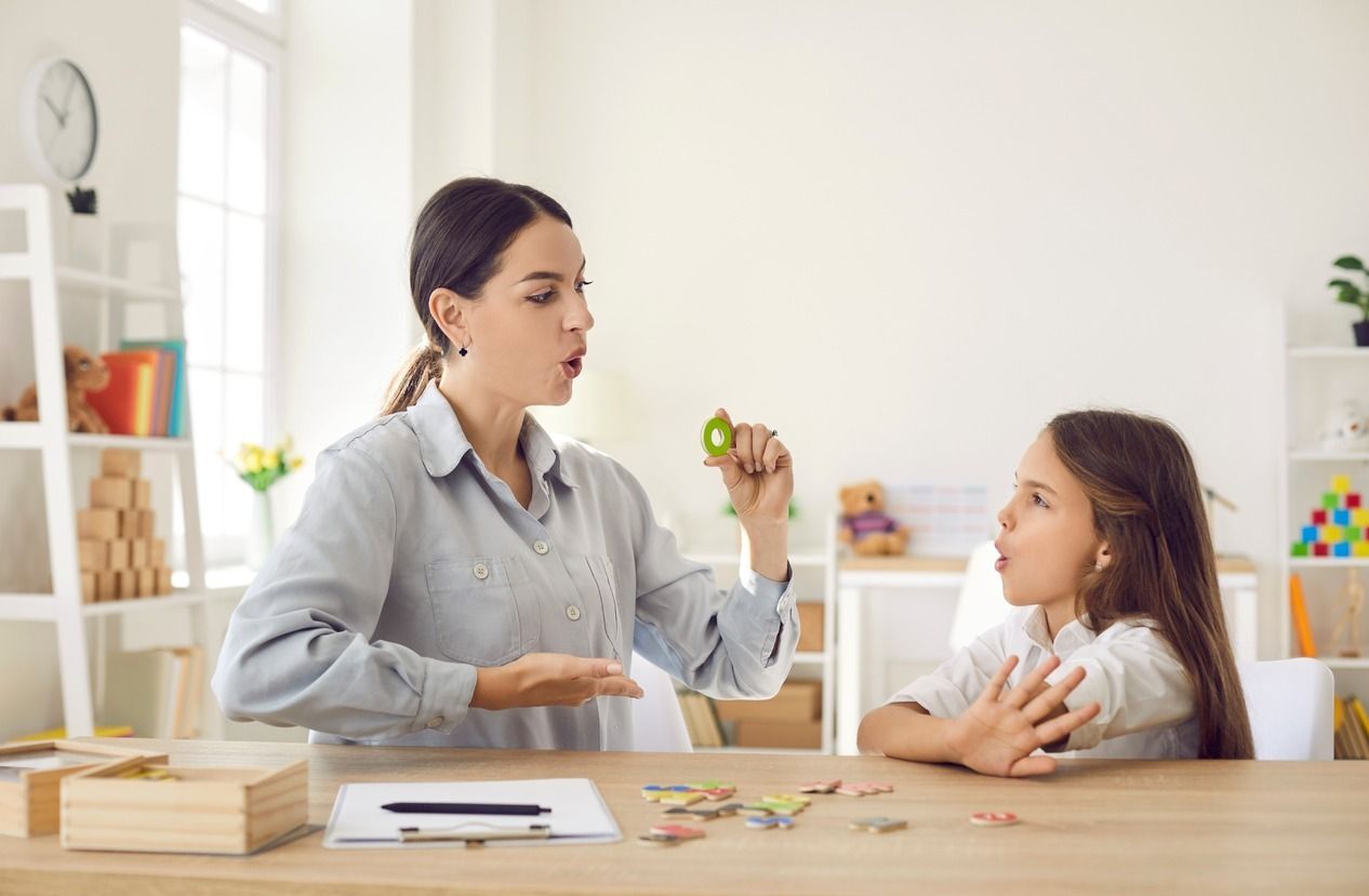 Una mujer está hablando con una niña mientras está sentada en una mesa.