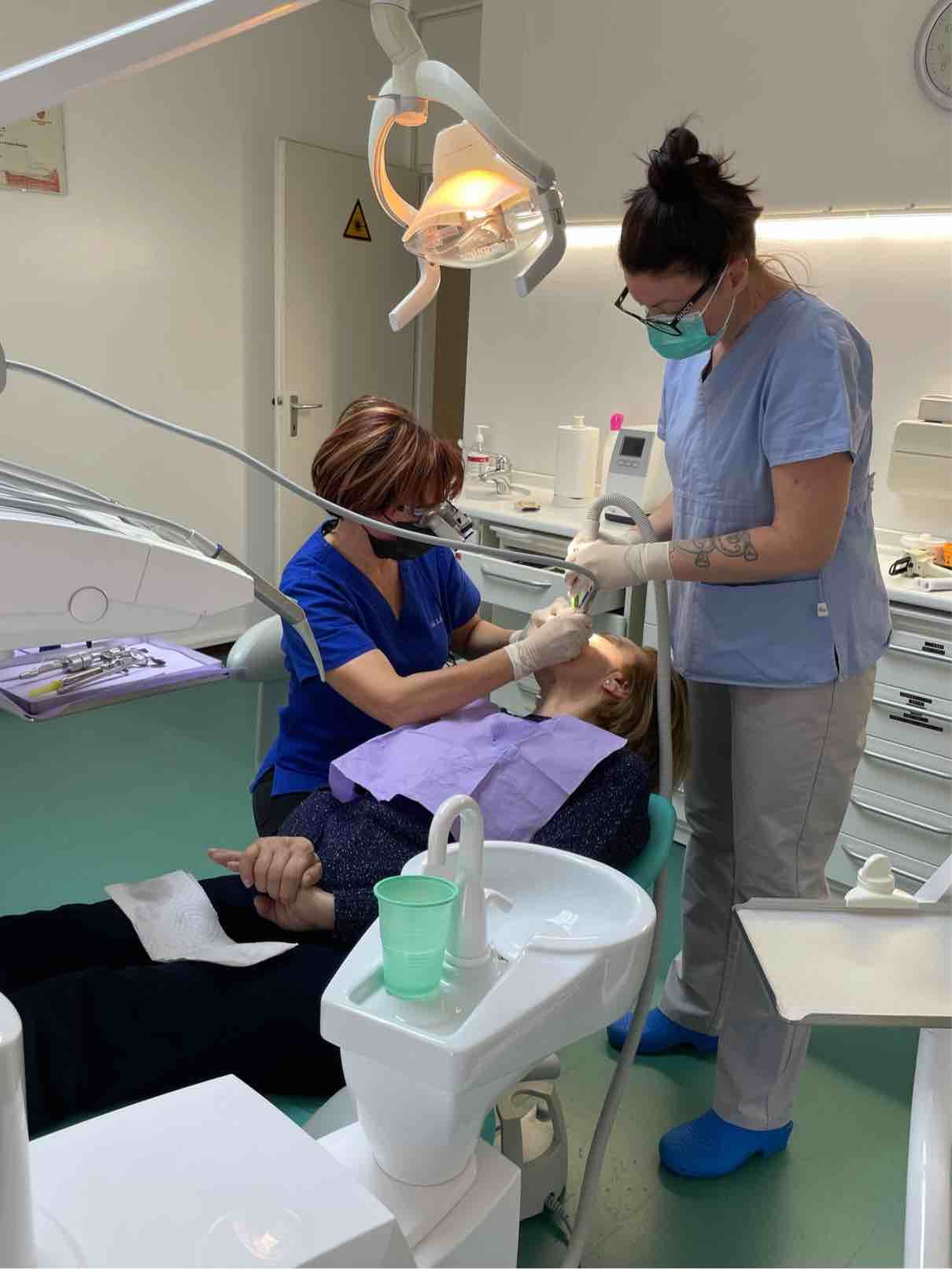 Il dentista e l’assistente, nello studio dentistico, effettuano un trattamento odontoiatrico.