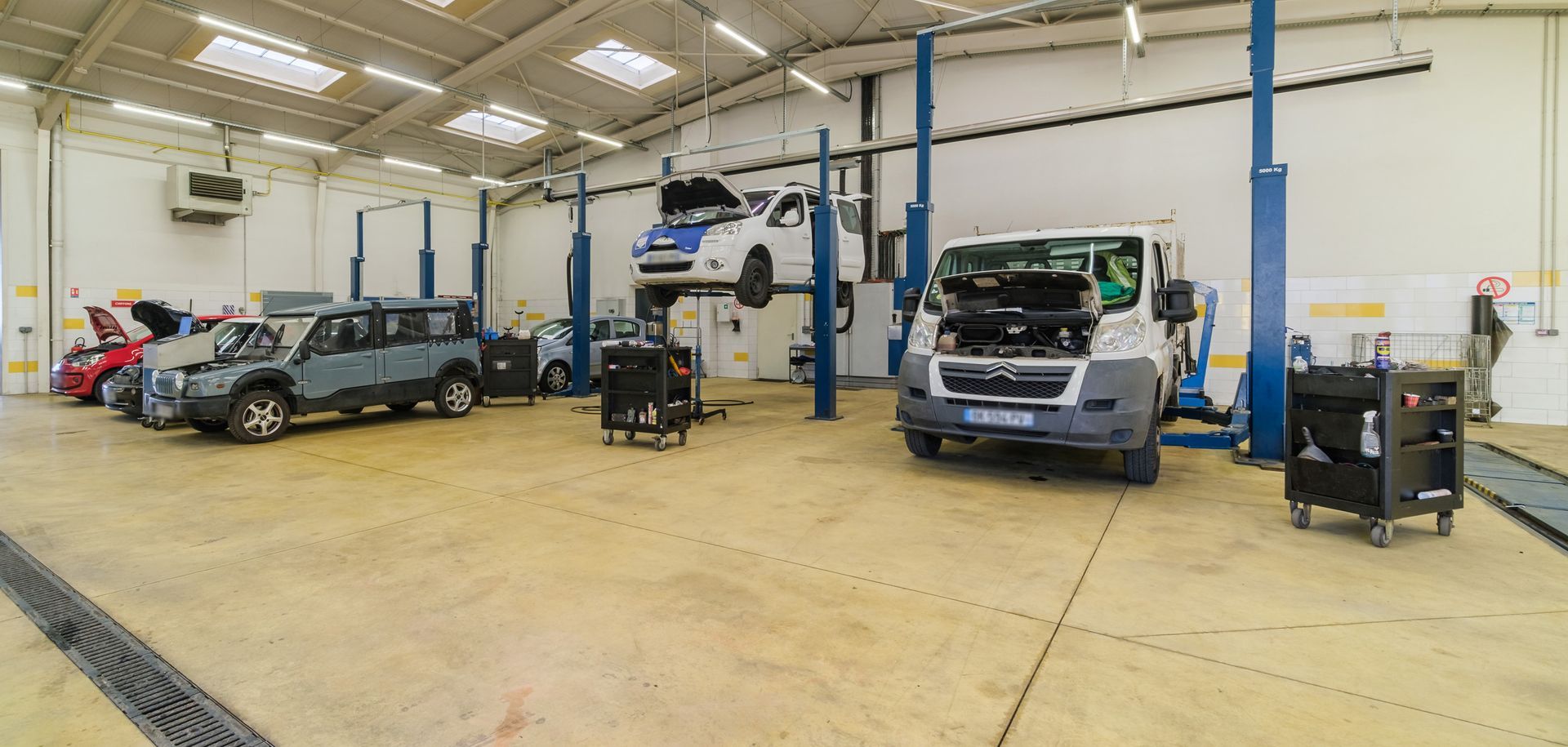 Intérieur du garage où des véhicules sont en réparation.