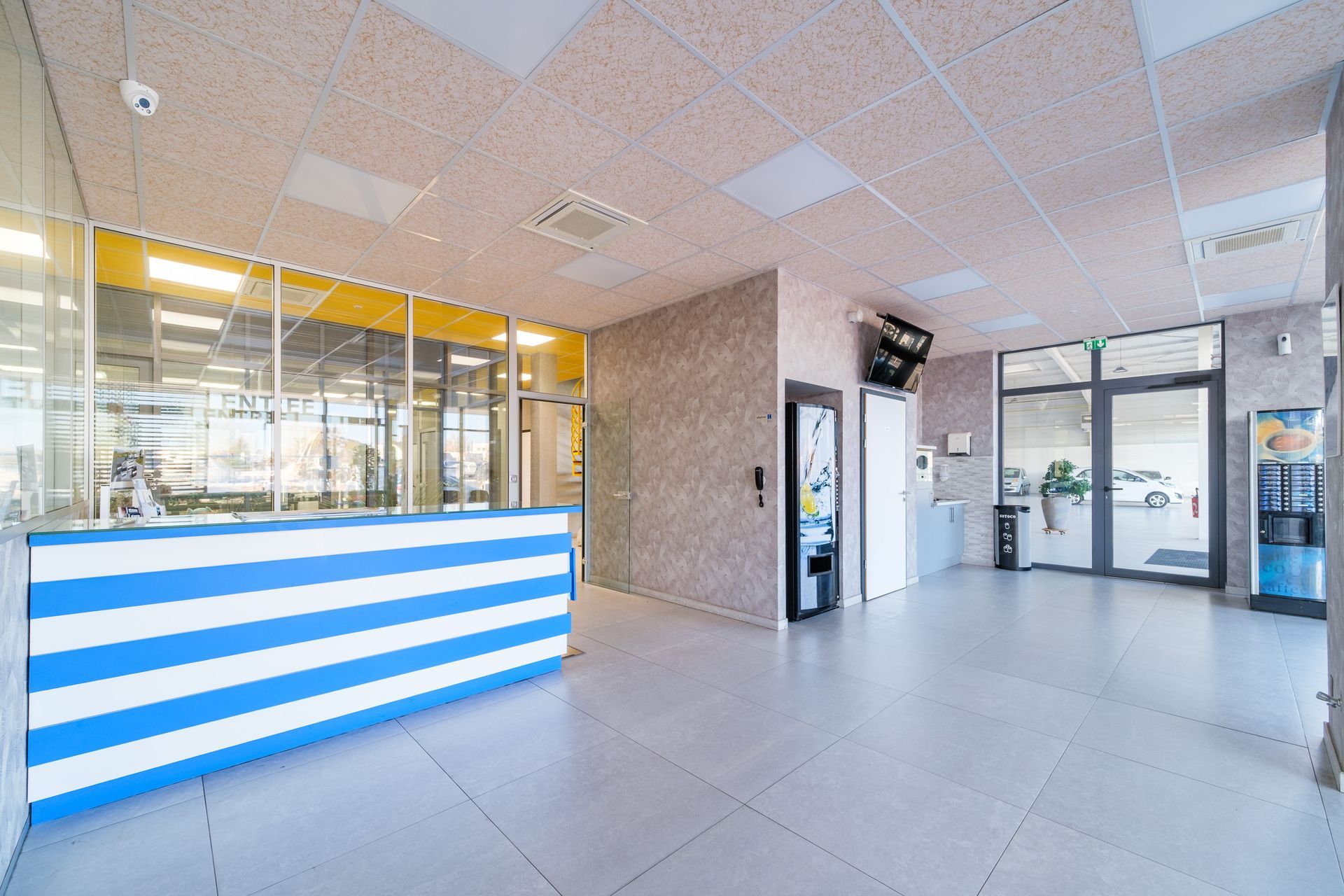 Hall d'accueil du garage Dépannage Josseron avec sur le côté droit des distributeurs de boissons et une télévision.