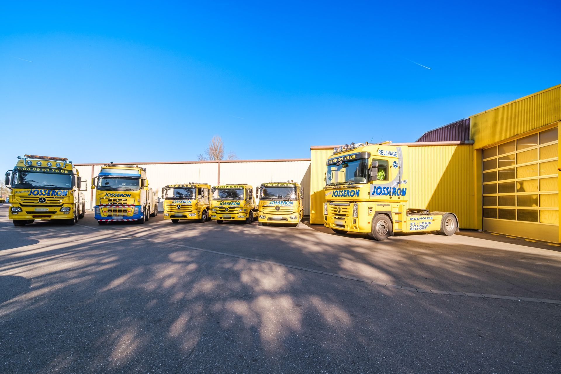 Six véhicules poids lourd de dépannage jaunes sur le parking.