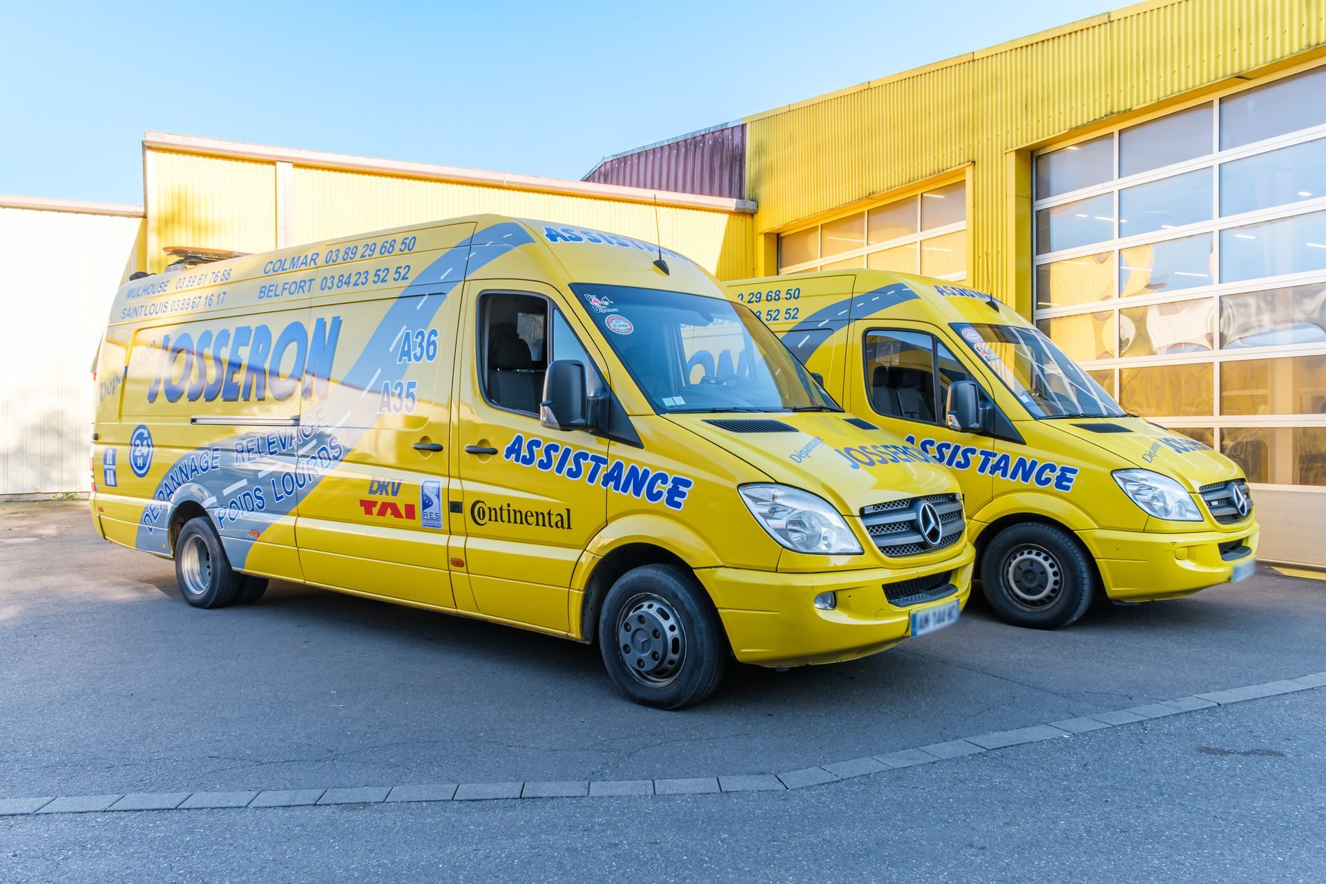 Deux véhicules utilitaires jaunes sur le parking.