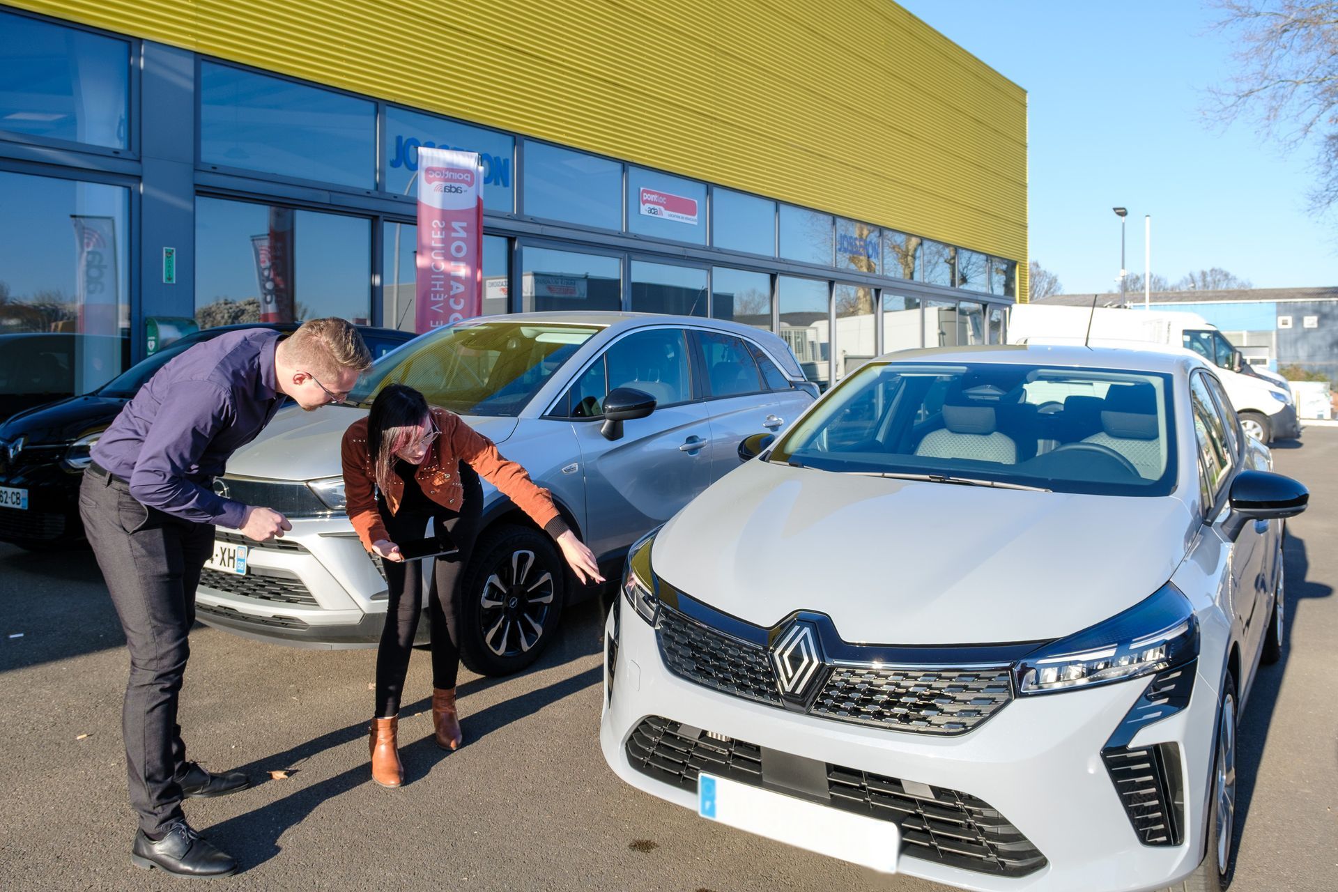 Deux personnes en train d'inspecter l'avant d'un véhicule Renault.