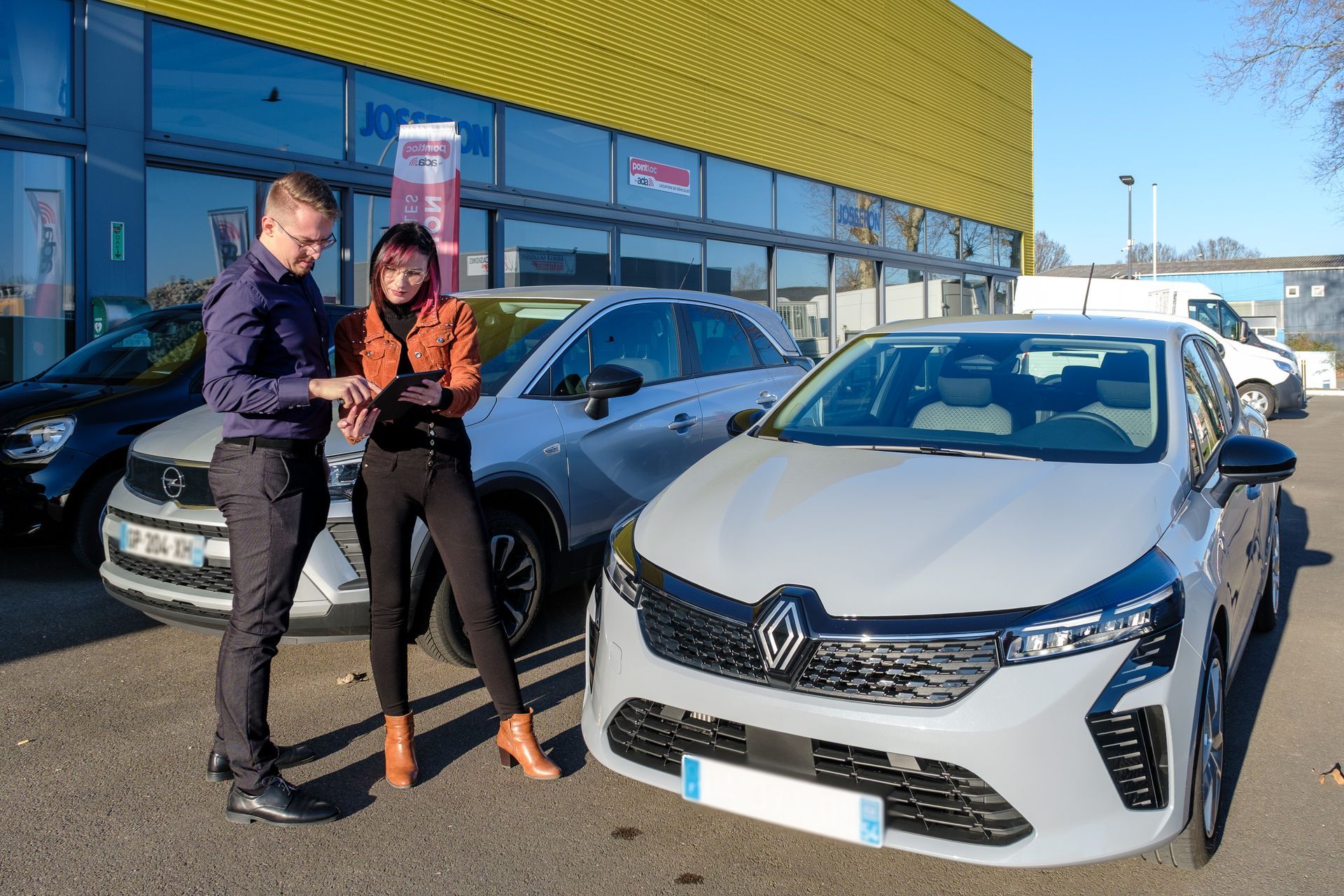 Deux personnes en train de lire des documents devant un véhicule Renault.