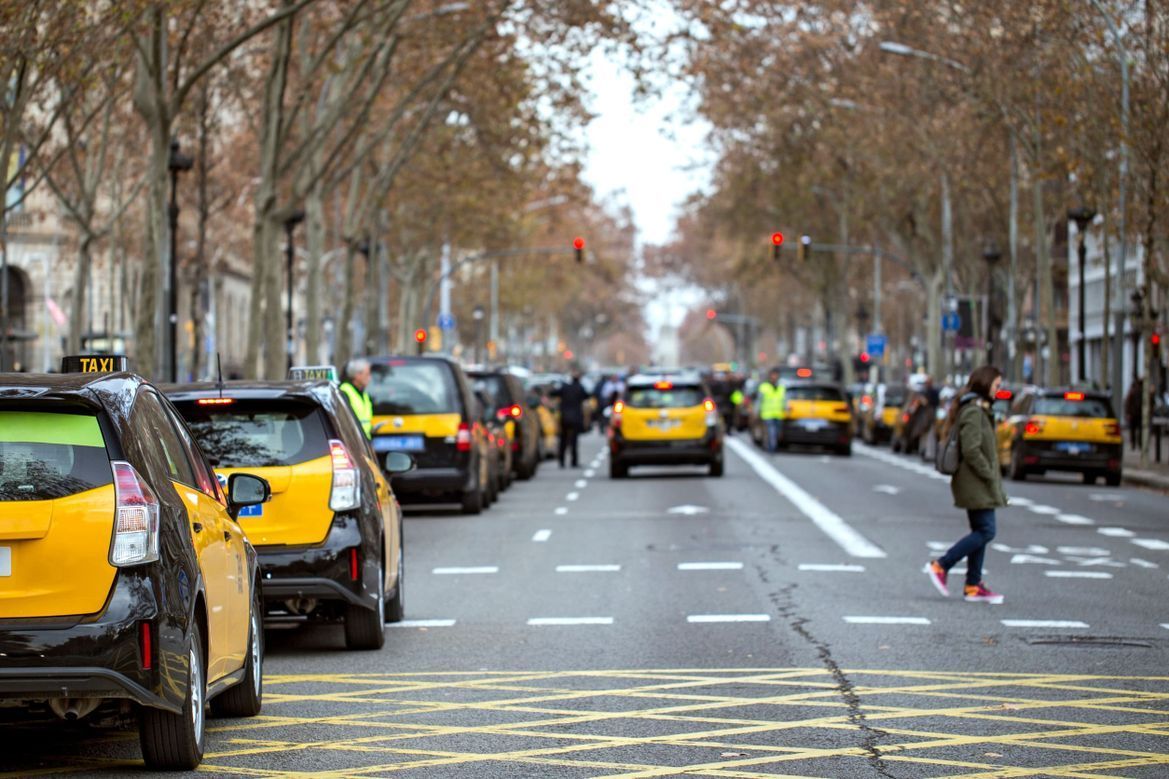 Una fila de taxis amarillos están estacionados al costado de una calle de la ciudad.