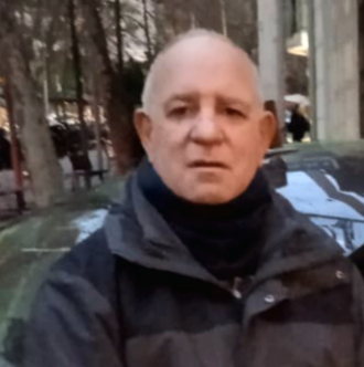 Un hombre que lleva una chaqueta Columbia se encuentra frente a un automóvil.