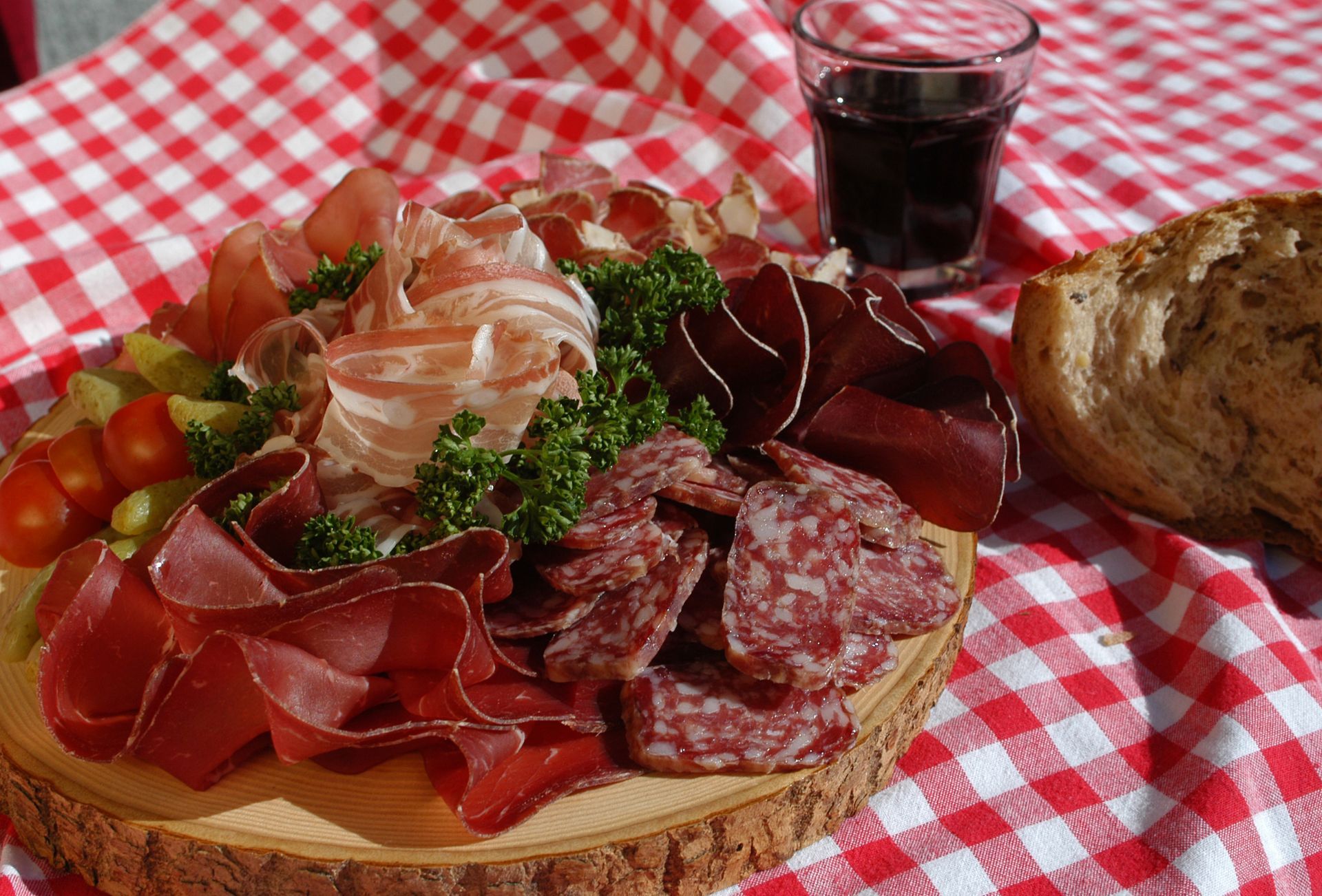 Aufgeschnittene Wurstspezialitäten auf einem rot-weiß-karierten Tuch, Spezialitäten-Metzg Splügen, Strub Orlando