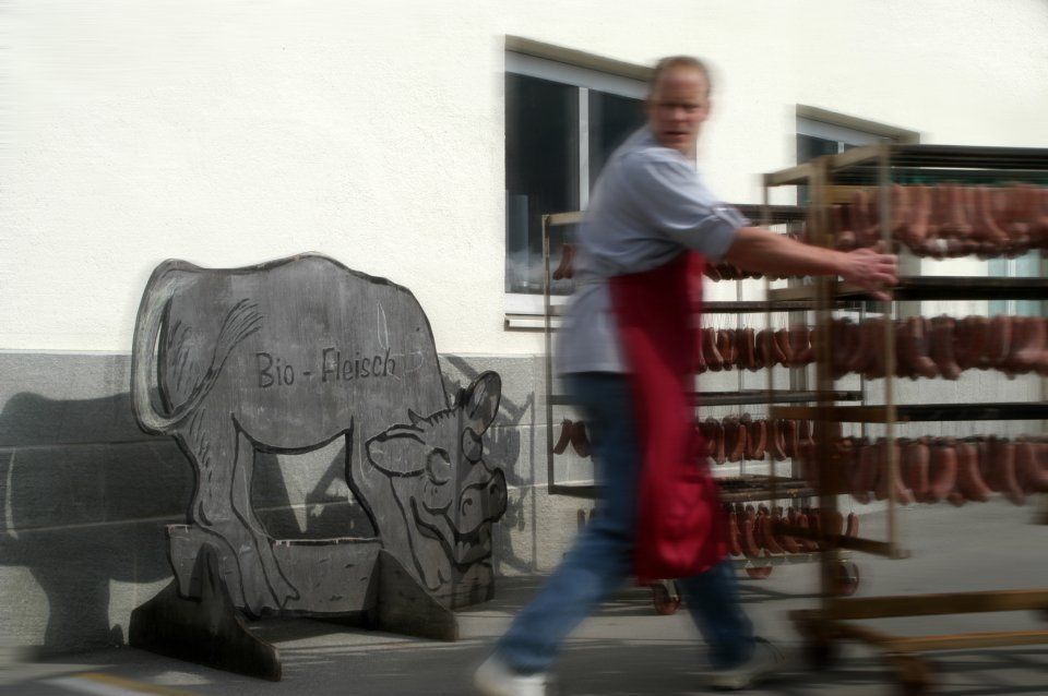 Mitarbeiter schiebt Wurstwagen, Mitarbeiter bei der Wurstproduktion, Spezialitäten-Metzg Splügen, Strub Orlando