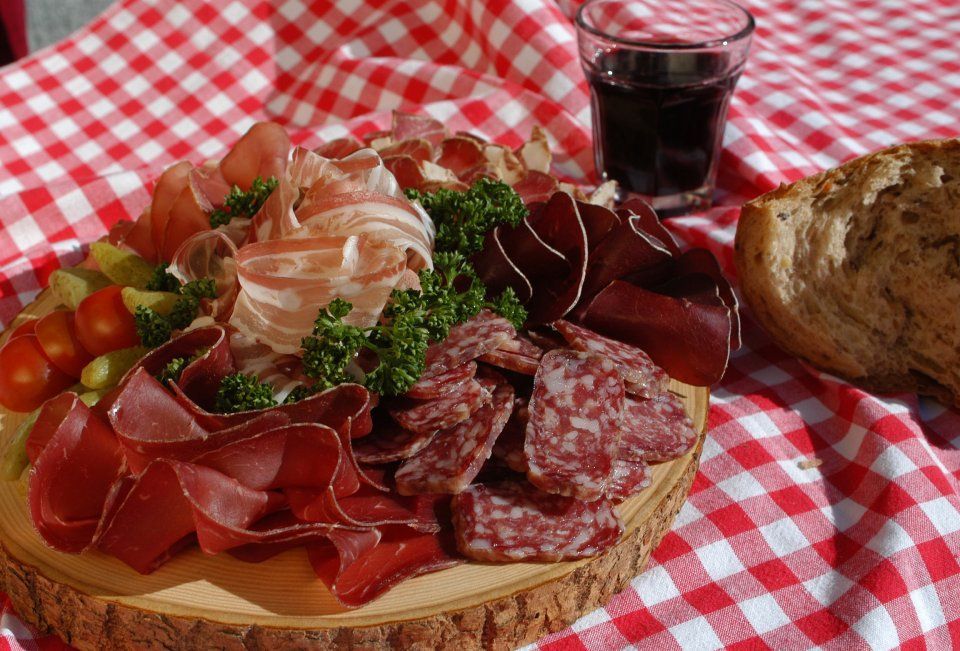 Appetitlich angerichtete Wurstspezialitäten, mit Rotwein, Brot und auf einer rot-weiß-karierten Decke, Spezialitäten-Metzg Splügen, Strub Orlando