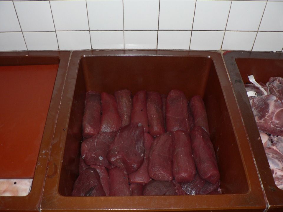 Eine Holzwanne mit Fleisch, Mitarbeiter bei der Wurstproduktion, Spezialitäten-Metzg Splügen, Strub Orlando