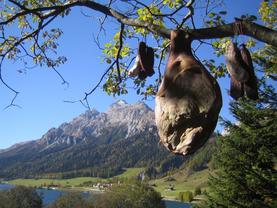 Laubbaum, an dem Fleisch hängt, Mitarbeiter bei der Wurstproduktion, Spezialitäten-Metzg Splügen, Strub Orlando