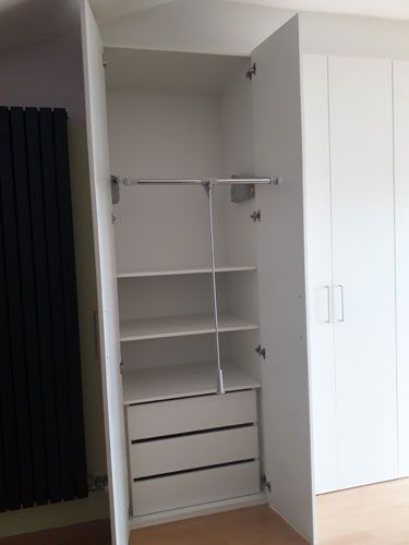 Un armario blanco con cajones y estantes en una habitación.