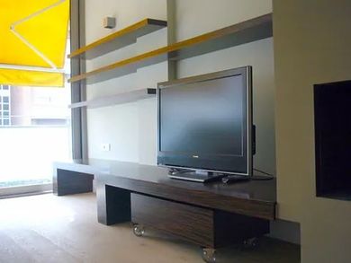 Un televisor de pantalla plana está sobre un centro de entretenimiento de madera.