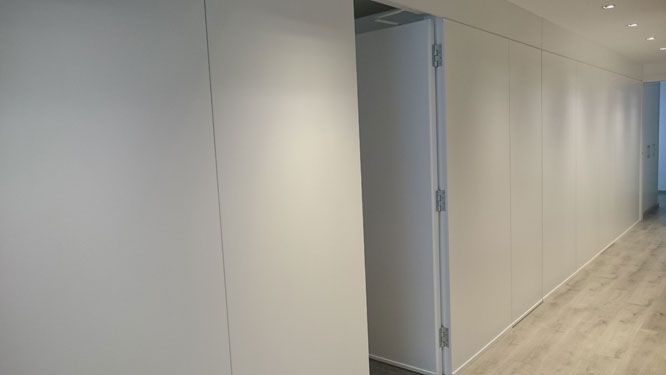 Un largo pasillo con paredes blancas y una puerta.