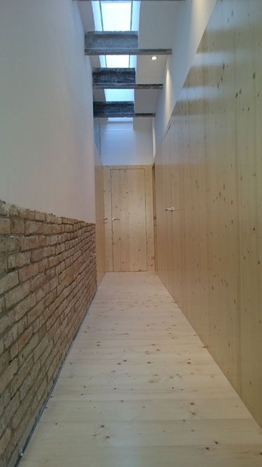 Un pasillo largo con suelo de madera y una pared de ladrillo.