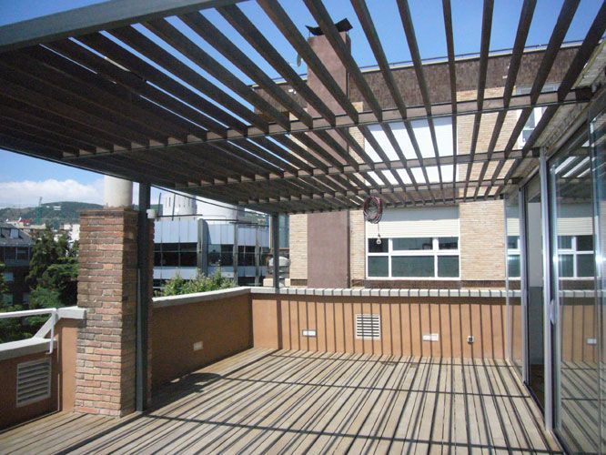 Una terraza en la azotea con pérgola y puertas corredizas de vidrio.