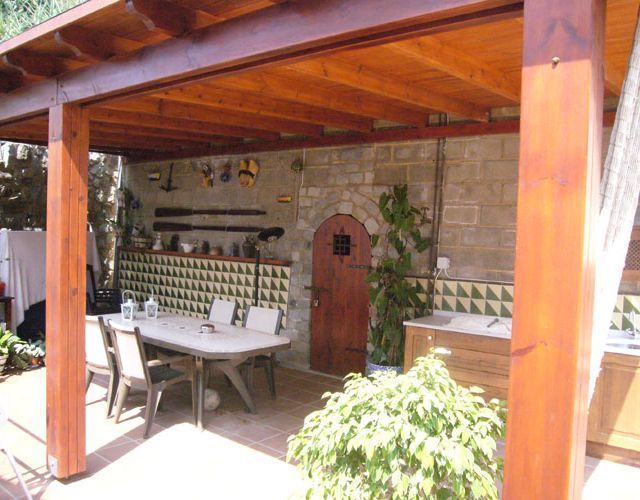 Un patio con mesa y sillas bajo un techo de madera.
