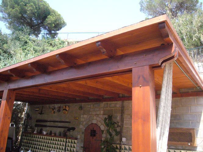 Una pérgola de madera con techo se encuentra encima de un edificio de ladrillo.