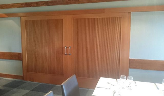 Un comedor con mesa y sillas y puertas corredizas de madera.