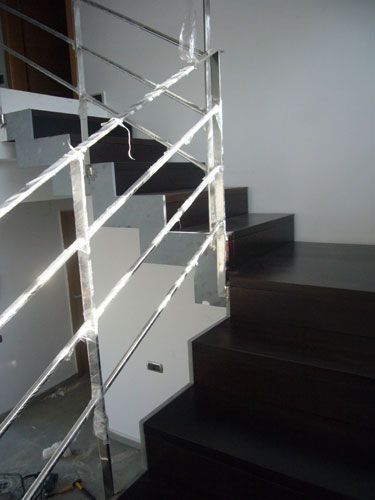 Una escalera con barandilla de acero inoxidable y escalones de madera