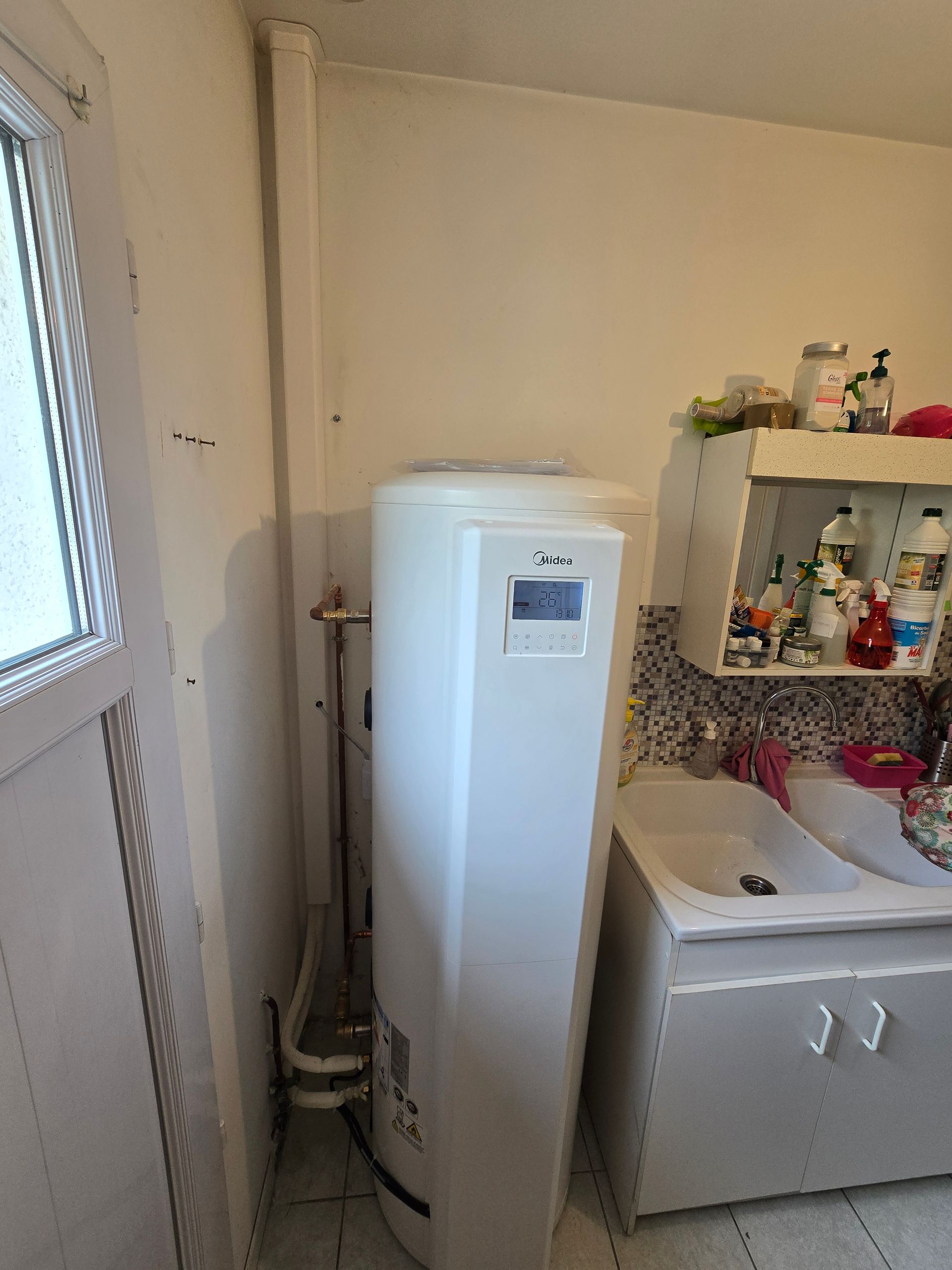 Système de pompe à chaleur blanc et noir avec un chauffe-eau et un réservoir rouge dans une buanderie.