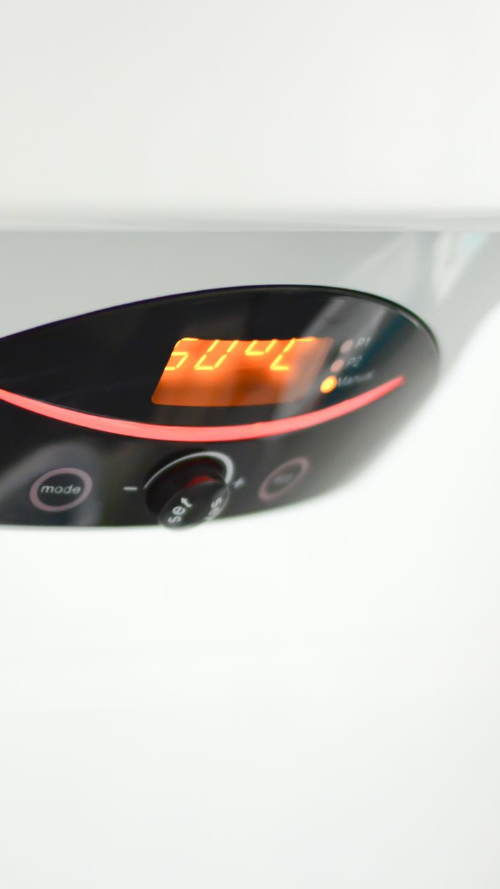 L'écran numérique d'un chauffe-eau affiche une température de 50 °C. Un bouton et des boutons se trouvent sous l'écran.