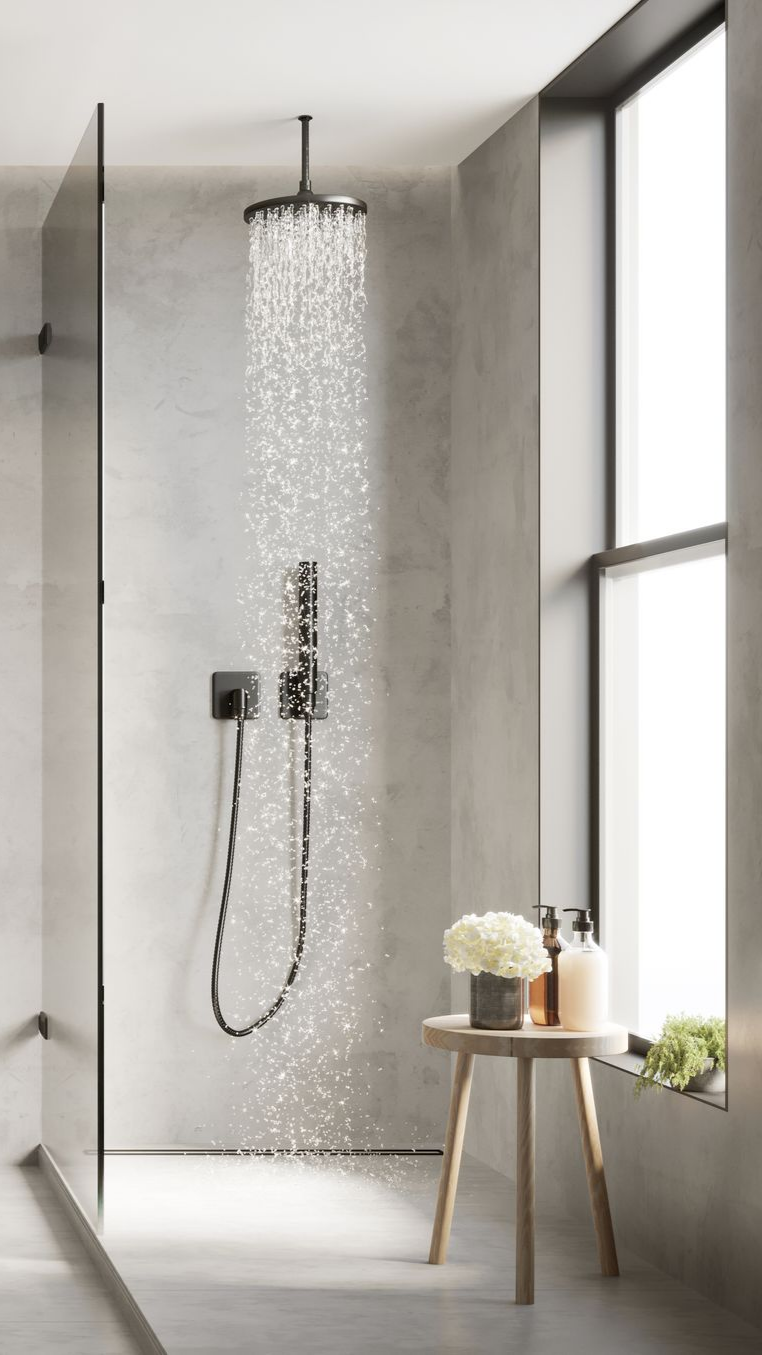 Douche avec robinetterie noire, paroi vitrée et fenêtre. Un tabouret en bois accueille des produits de toilette et une plante.