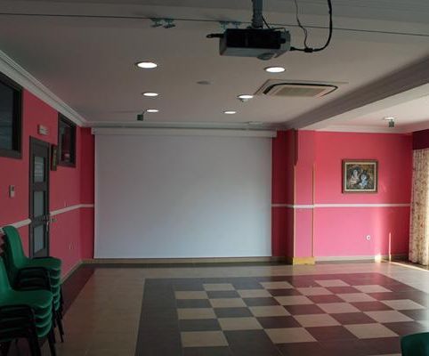 Una habitación vacía con paredes rosas y un proyector en el techo.