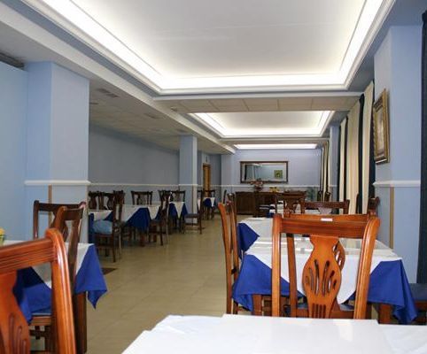 Un comedor con mesas y sillas y un mantel azul.