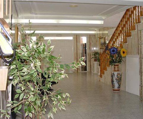 Un largo pasillo con escaleras y un jarrón de flores.