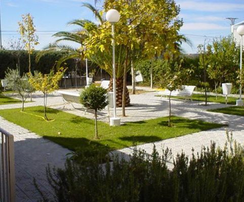 Un exuberante parque verde con árboles y bancos en un día soleado.