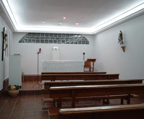 Una iglesia con bancos de madera y un altar blanco