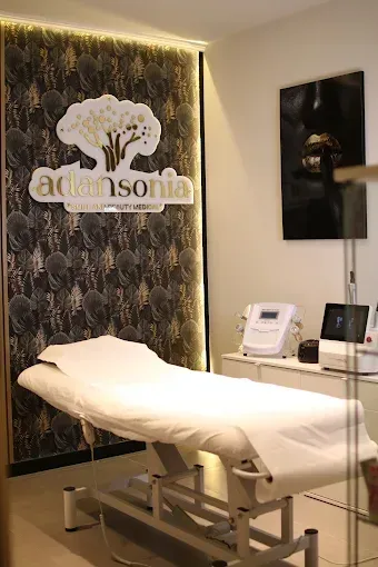 Interior de spa con cama de tratamiento, equipamiento y decoración de pared con logotipo.