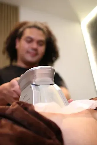 Persona que administra un tratamiento de contorno corporal con un dispositivo en un entorno clínico.