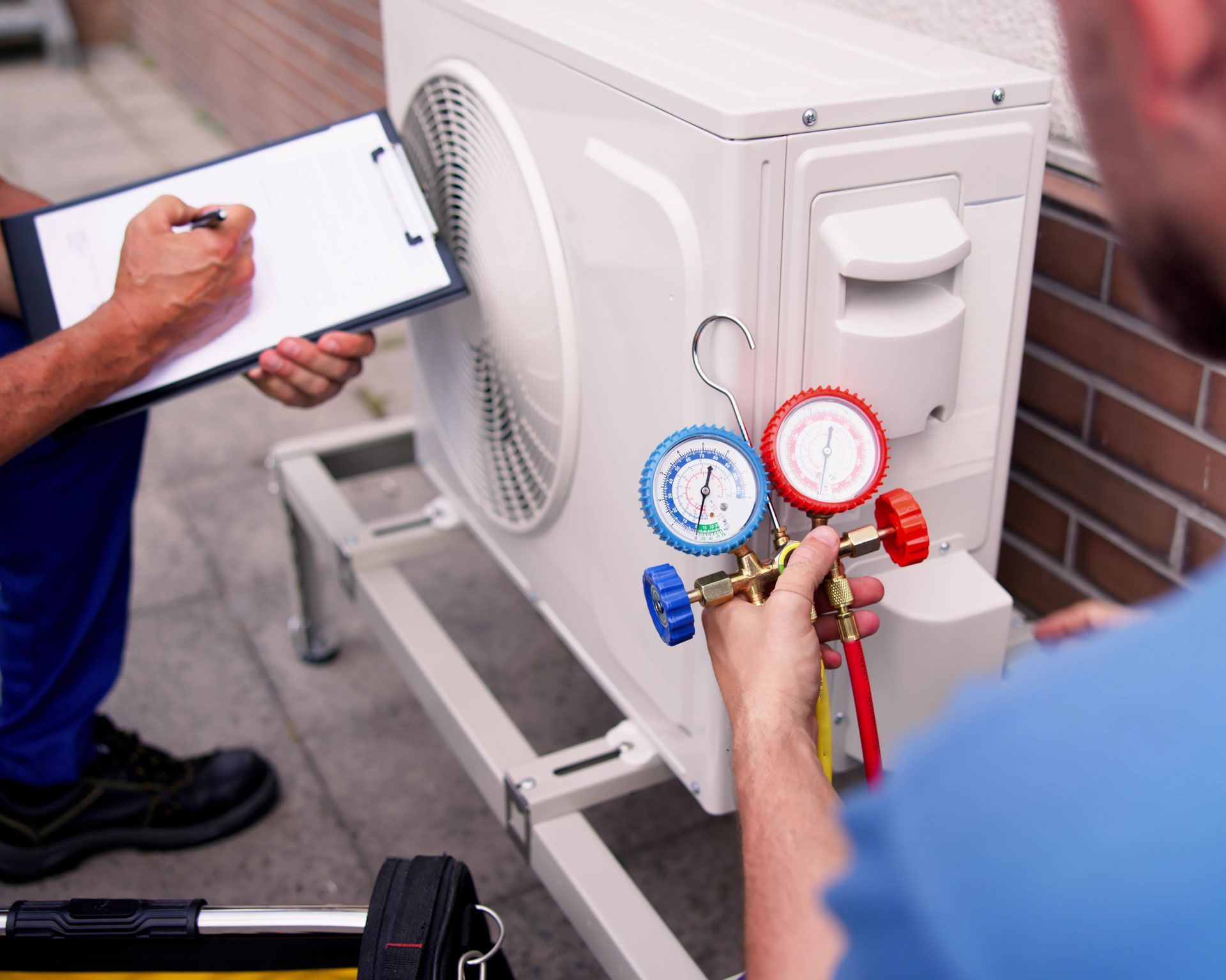Deux techniciens contrôlant les fluides frigorigènes d'une unité extérieure de climatisation