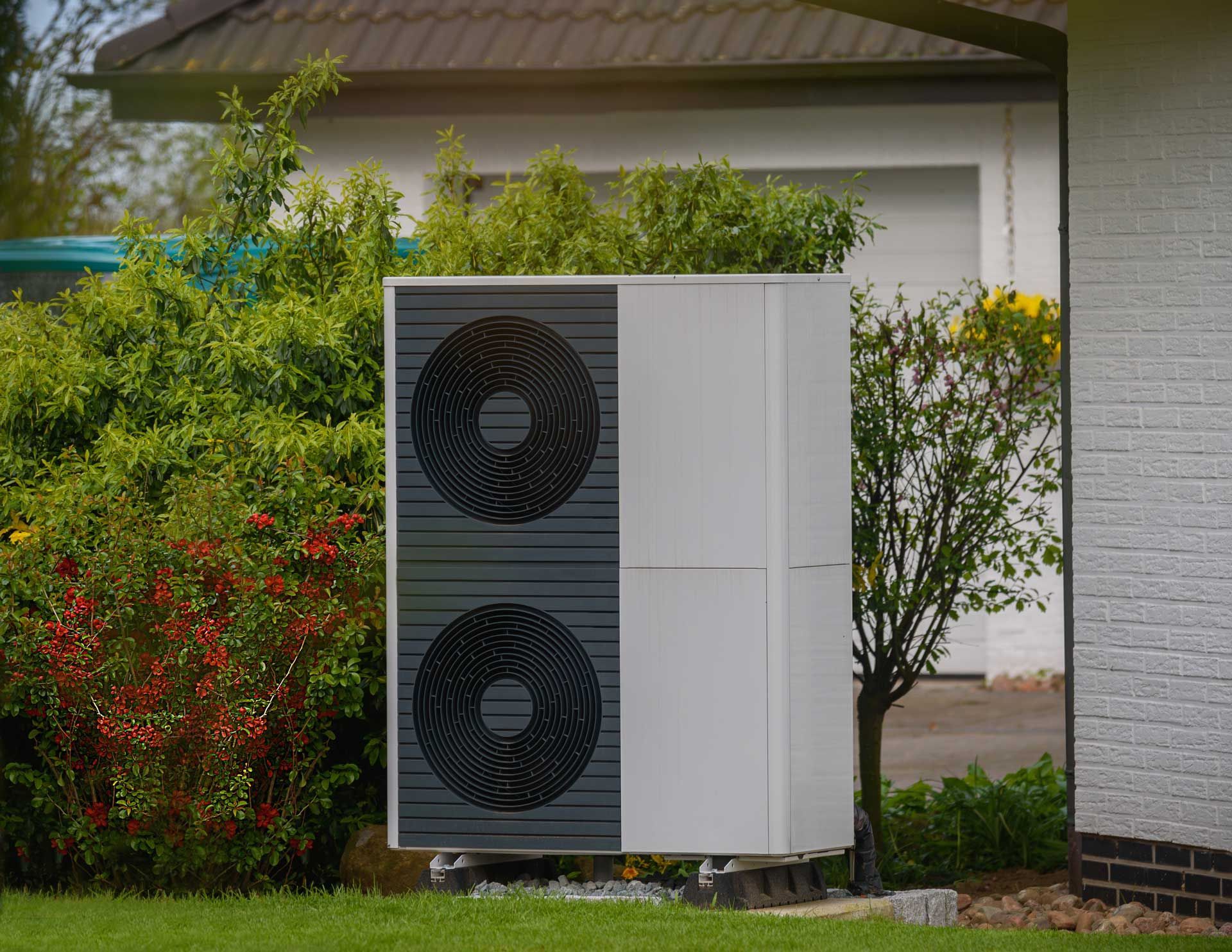 Une pompe à chaleur à l'arrière d'une maison avec jardin