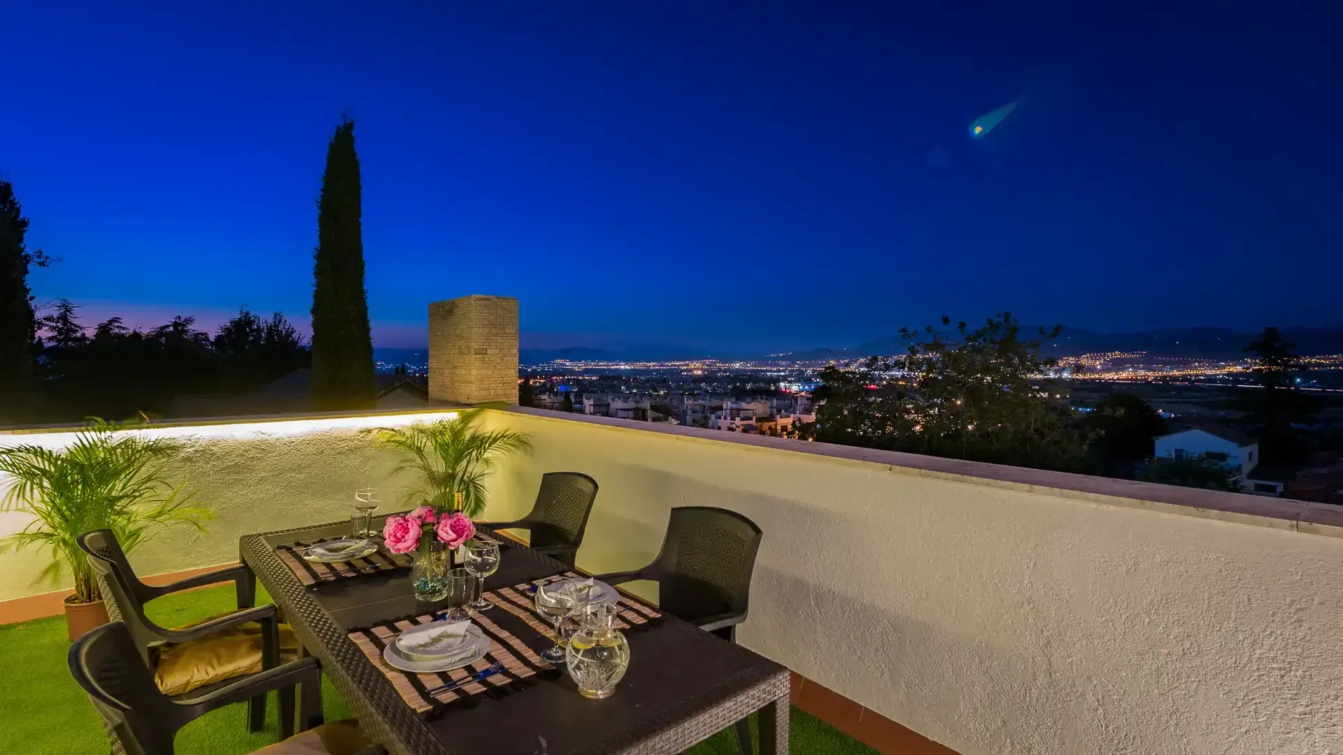 Comedor al atardecer en el patio con luces de la ciudad