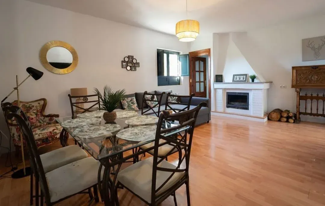 Sala de estar con mesa de comedor, sillas, chimenea y piso de madera noble.