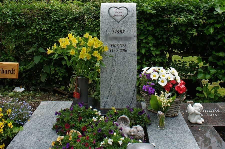 Ein Grab mit Blumen und einem Schild mit der Aufschrift