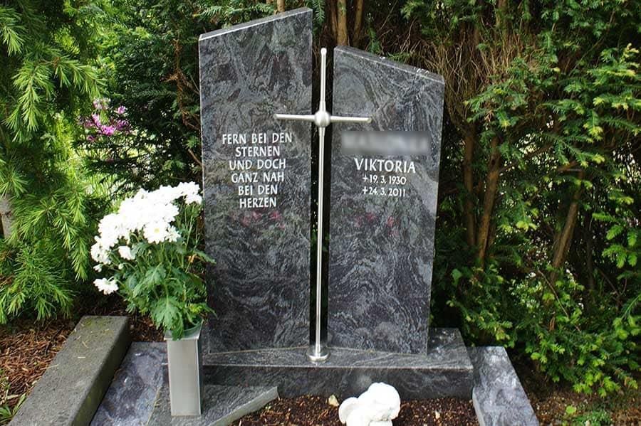 Ein Grabstein mit einem Kreuz und Blumen davor