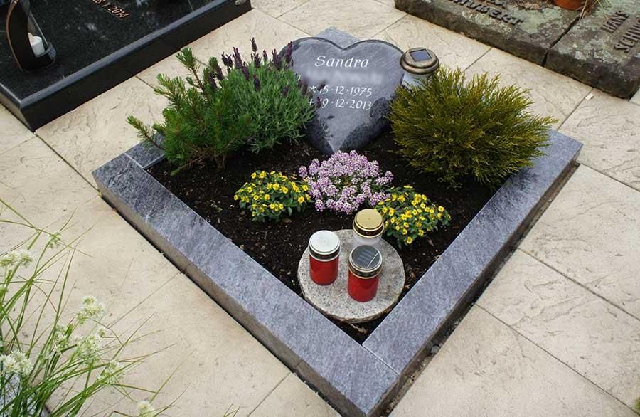 Ein Grab mit einem herzförmigen Grabstein und Blumen