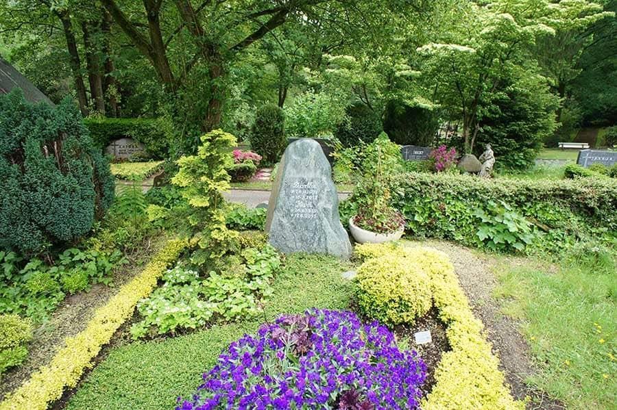 Ein Friedhof mit lila Blumen und einem großen Felsen in der Mitte