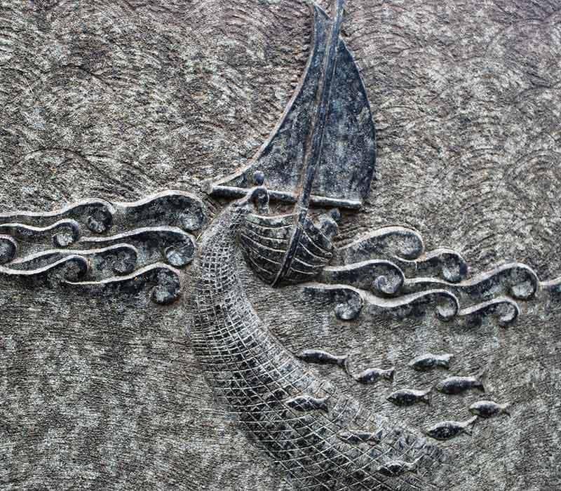 Eine Skulptur eines Segelboots und Wellen an einer Wand.