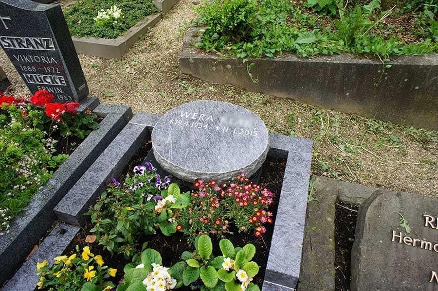 Ein Grab auf einem Friedhof mit Blumen und einem Stein in der Mitte