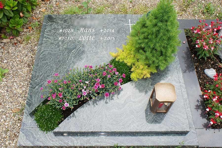 Ein Grab mit Blumen und einer Kerze darauf