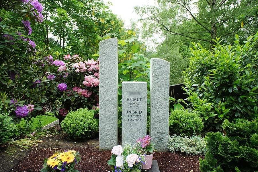 Ein Grab in einem Garten mit Blumen und Bäumen