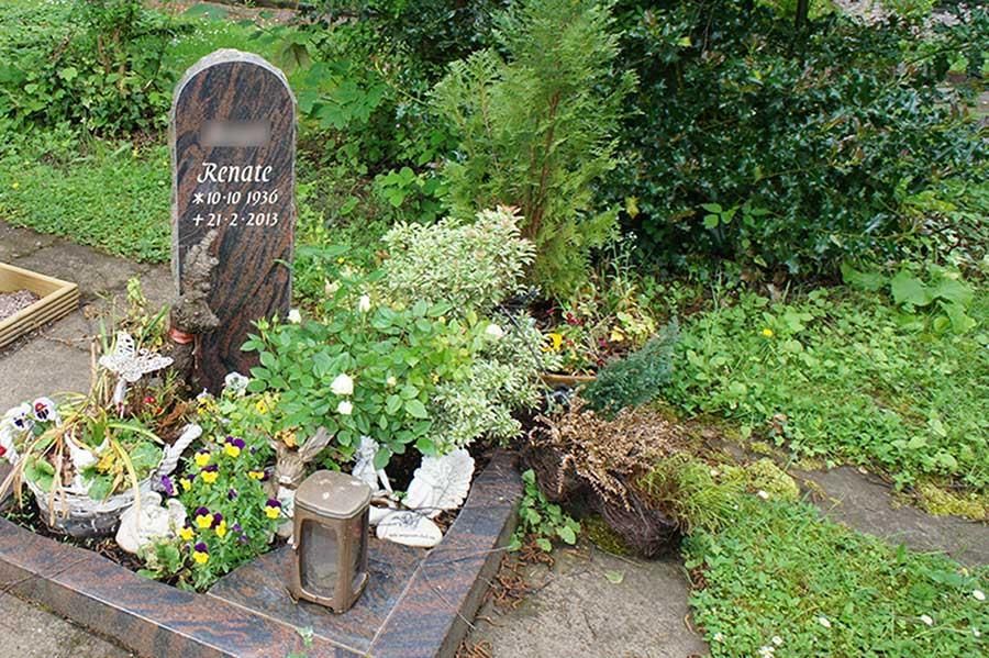 Ein Friedhof mit einem Grabstein und Blumen darin