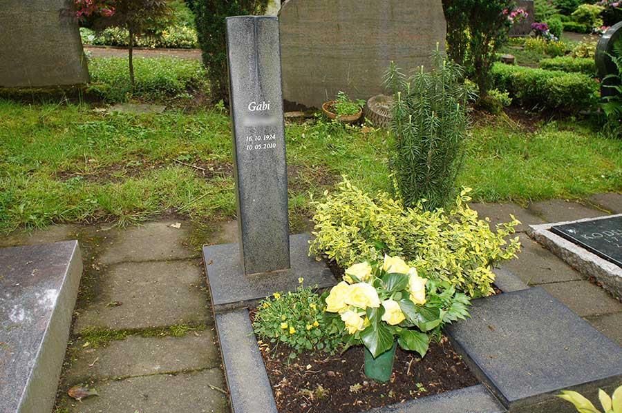 Ein Grab auf einem Friedhof mit Blumen und einem Kreuz