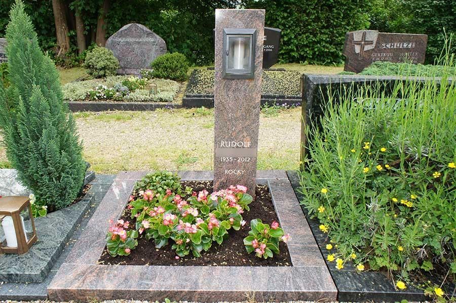 Ein Grab auf einem Friedhof mit Blumen und einem Schild mit der Aufschrift „Prince“